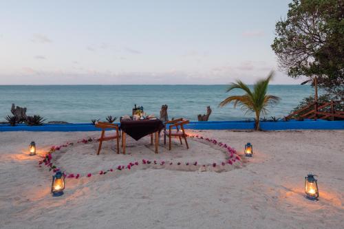 吉汶瓦Moja Tuu The Luxury villas & Nature Retreat的沙滩上的桌子,沙滩上灯火通明