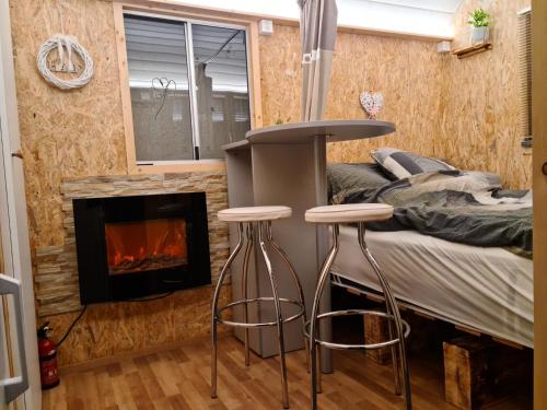TraversLa roulotte的一间卧室设有一张床,壁炉前设有两张凳子