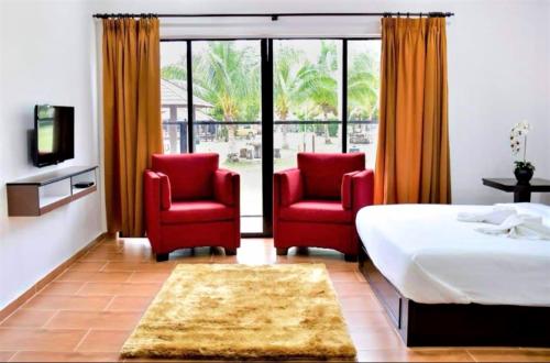 Kampung MawarTELUK PENYABUNG RESORT的一间卧室配有两张红色椅子和一张床