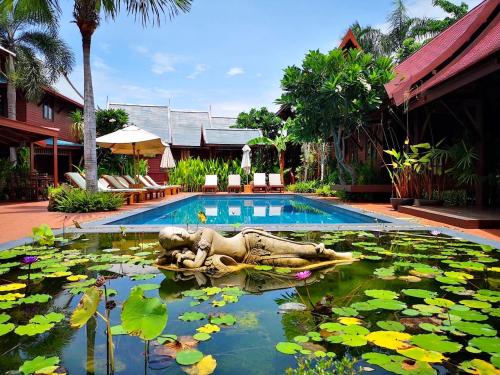 华欣卢恩卡诺克泰屋度假酒店的水中一座有雕像的游泳池,里面装有百合花