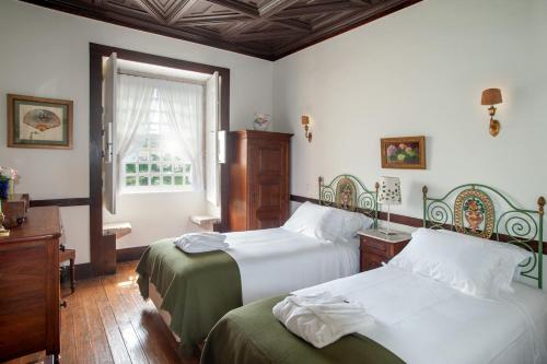 圣玛尔塔迪佩纳吉昂Casa do Salgueiral的一间卧室设有两张床和窗户。