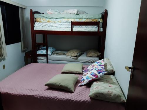 大普拉亚Alto Padrão com 94 mtrs - Frente Mar - sacada com Vista Mar的卧室配有两张双层床、粉红色床单和枕头。