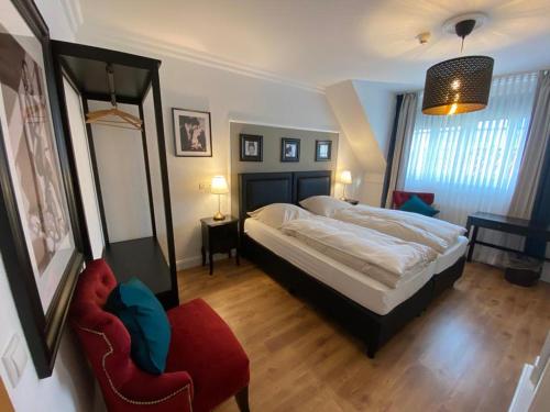 库阿肯布吕克Hotel Hagspihl的一间卧室配有一张大床和一张红色椅子