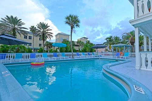 维洛海滩The Islander Inn的度假村的游泳池,设有蓝色的椅子和棕榈树