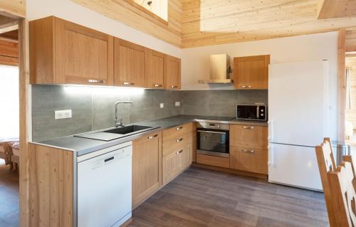 里蒙纽耶Odalys Chalet D'Alice的厨房配有木制橱柜和白色冰箱。