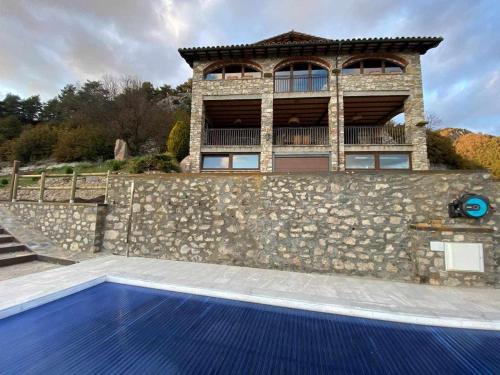GombrenyMas merolla casa para descanso familiar的一座带石墙和蓝色游泳池的房屋