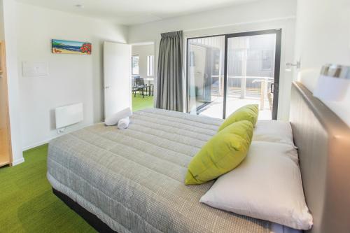 怀普外埔湾营地酒店的一间卧室配有一张带黄色枕头的床和一个阳台