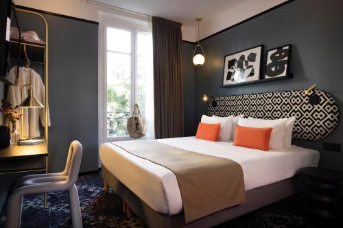 巴黎夏洛特宫殿酒店的一间卧室配有一张带橙色枕头的大床