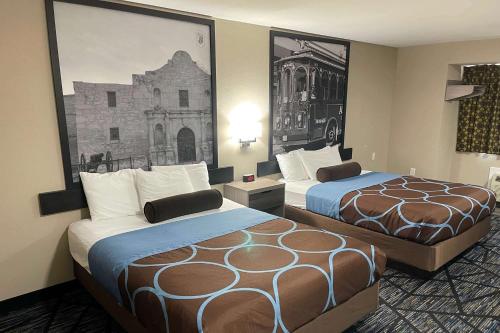 圣安东尼奥Super 8 by Wyndham San Antonio Downtown NE的酒店客房设有两张床,墙上挂着一张照片。