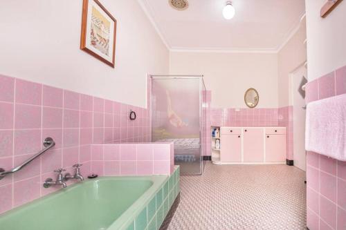 诺瑟姆River Views in the Heart of Town的粉红色的浴室设有浴缸和粉红色的瓷砖
