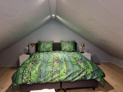 蒙尼肯丹De Rokerij的阁楼上一张带绿色棉被的床