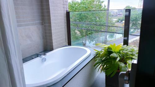 罗东镇川岸空中Villa的带浴缸的浴室和种植了植物的窗户