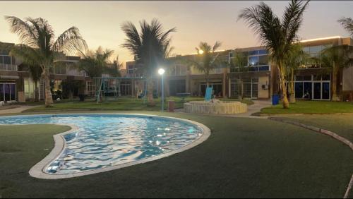 欧普尔شاليه جزيره السعاده的棕榈树建筑前的游泳池