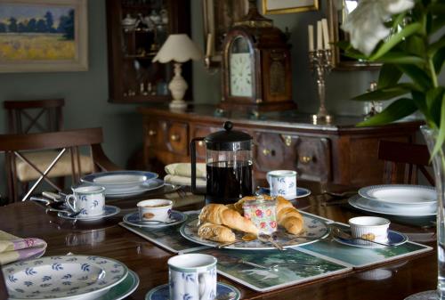 哈尔福德The Old Manor House的一张桌子,上面放着一盘羊角面包和咖啡壶