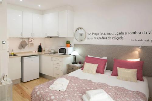 里斯本Central Studio的一间卧室配有带粉红色枕头的床,还设有一间厨房
