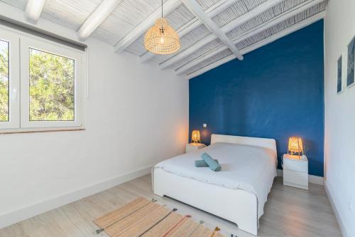 Mexilhoeira GrandePalmeiras Cottages的卧室配有白色的床和蓝色的墙壁