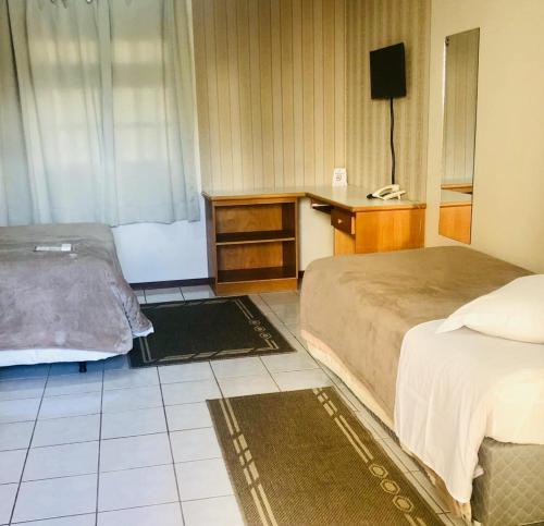 拉热斯Villa Apart Hotel的一间卧室配有两张床、一张桌子和一台电视。