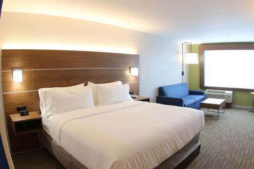 利沃尼亚Holiday Inn Express & Suites - Detroit Northwest - Livonia, an IHG Hotel的酒店客房带大床和蓝椅