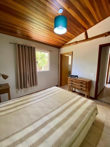 德尔菲诺波利斯Casa em Área Rural - Delfinópolis的一间卧室设有一张大床和木制天花板