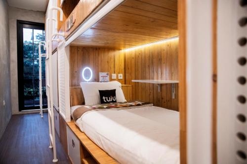 雅加达Tuju Arteri Pods的卧室配有一张床铺,位于带木墙的房间内