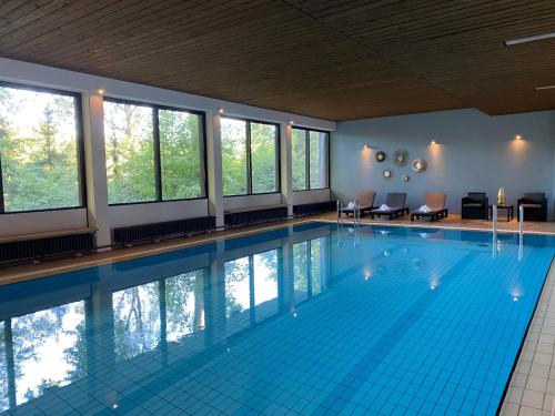 吕特延堡达斯奥斯特斯布里克酒店的大型游泳池设有蓝色瓷砖地板和窗户。