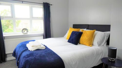 伍尔弗汉普顿Spacious 3 bed house, great for FAMILIES and CONTRACTORS, sleeps 5 plus FREE Parking - Triumph Serviced Accommodation Wolverhampton的一间卧室配有一张大床,提供黄色和蓝色的枕头
