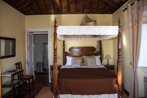 Estreito de Câmara de LobosVila Afonso的卧室配有带枕头的木制天蓬床