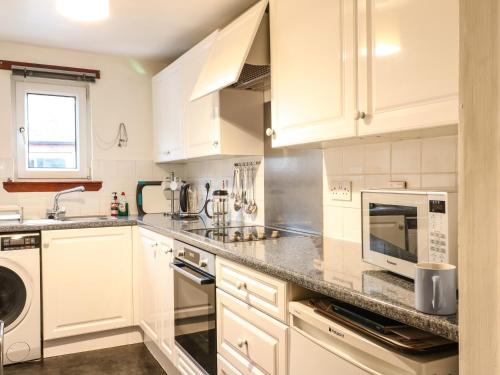 阿伯福伊尔Aberfoyle Apartment的厨房配有白色橱柜、水槽和微波炉