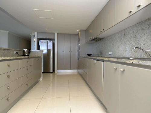 尼尔森湾Oasis Unit 9 5 Laman Street的厨房配有白色橱柜和不锈钢冰箱