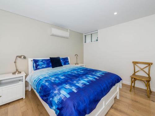 浅滩湾The Shoal Unit 405 Shoal Bay的白色卧室配有蓝色的床和一张桌子