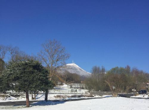 奥尔西讷Appart' Côté Puy-de-Dôme的山底下有雪覆盖的山丘