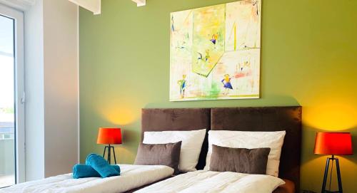 梅特曼BESOTEL Mettmann的一间卧室配有一张带两盏灯和一幅画的床铺