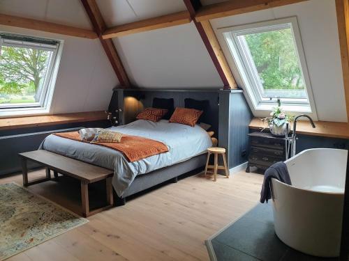 DiffelenB&B Het Nijenhuis的一间卧室设有床、两个窗户和一个浴缸