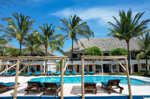 MakunduchiNest Style Beach Hotel Zanzibar的一个带椅子和棕榈树的度假游泳池