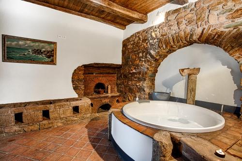 皮诺拉瓦Dimora storica Giorni resort & spa的一间石墙内大浴室,配有浴缸