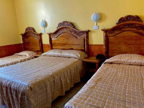 杜兰戈Hotel Nuevo Centenario的一间卧室设有两张床,墙上有两盏灯。