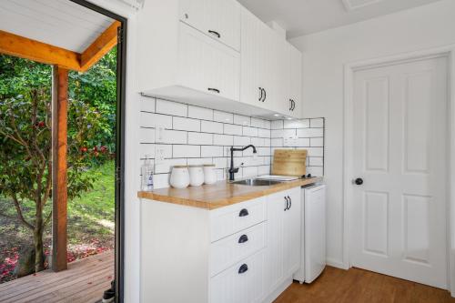 阿卡罗阿Woodside - Akaroa Holiday Cottage的厨房配有白色橱柜和水槽