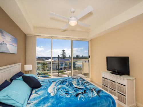 安特兰斯Ocean Views Unit 15的卧室设有大窗户、一张床和电视。