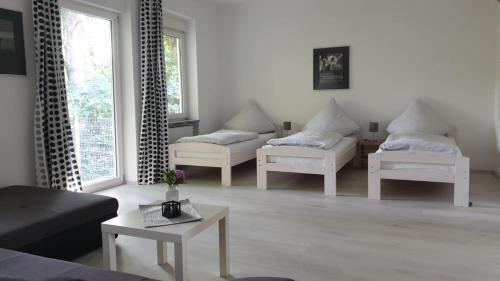 盖尔森基兴Naturfreundehaus Gelsenkirchen的客厅配有3把白色椅子和桌子