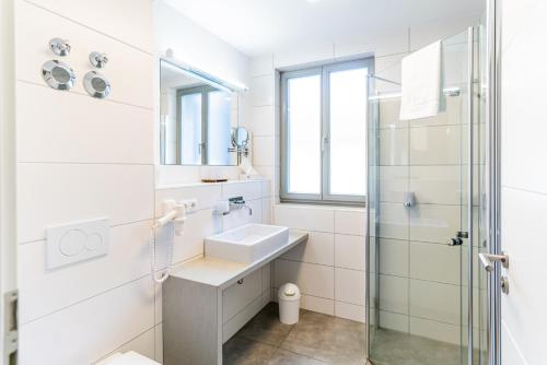 埃朗根格劳尔沃夫老城酒店的白色的浴室设有水槽和淋浴。