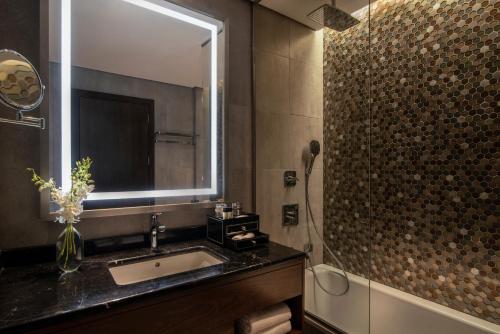 利雅德Movenpick Hotel and Residences Riyadh的一间带水槽、镜子和淋浴的浴室
