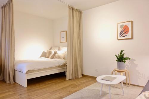 科布伦茨NEU - gemütliches und modernes Apartment mit Stellplatz的白色卧室配有床和桌子