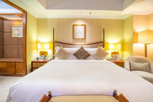青岛青岛颐中皇冠假日酒店的卧室配有一张白色大床和两把椅子