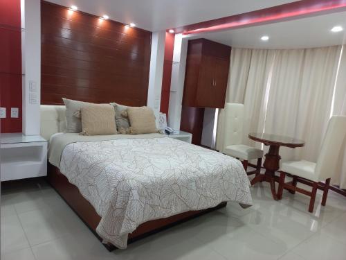 瓦曼特拉La Aurora Hotel Like Home的卧室配有1张床和1张桌子及椅子