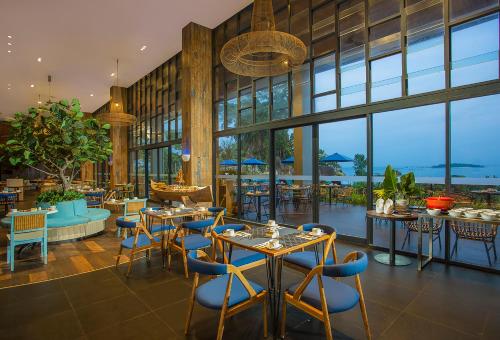 TanjungbingaSwiss-Belresort Belitung的餐厅设有桌椅和窗户。