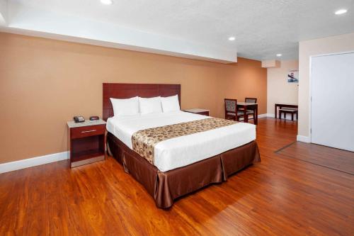 海港城Travelodge by Wyndham Harbor City的一间卧室配有一张大床和一张桌子及椅子