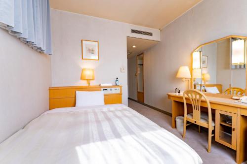 小山市小山宫经济型酒店的一间卧室配有一张床、一张书桌和一面镜子