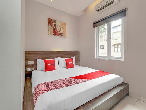 万隆Super OYO Capital O 90726 The Regia Cihampelas Hotel的一间卧室配有一张带红色枕头的大床