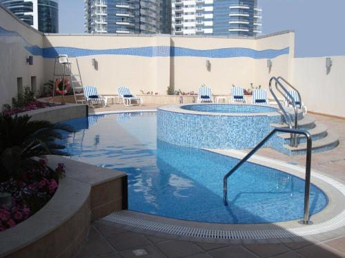 迪拜迪拜豪景园公寓式酒店的大楼内带椅子的大型游泳池
