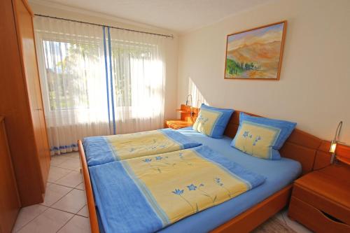 瓦伦Ferienhaus Waren SEE 6941的一间卧室配有一张带蓝色床单的床和一扇窗户。